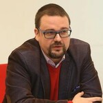 Zdjęcie Krzysztofa Czechowskiego redaktora naczelnego kwartalnika. Mężczyzna w średnim wieku w okularach z zarostem, siedzacy przy stole w granatowej marynarce i koszuli.