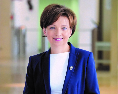 Elegancka uśmiechnięta kobieta w niebieskiej marynarce. Minister Rodziny i Polityki Społecznej Pani Marlena Maląg